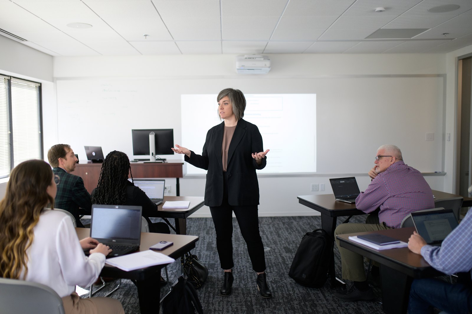 Instructor leading a small class of professionals working on laptops